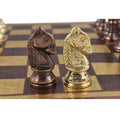 A detailed look at the copper and gold brass knights facing each other on the patterned metal board.