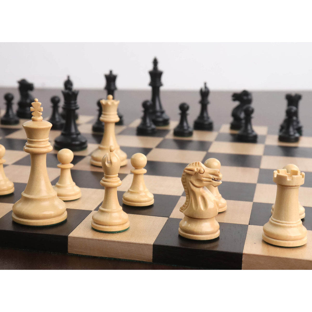 Perspective view of weighted boxwood chess pieces positioned on a dark wooden chess board.