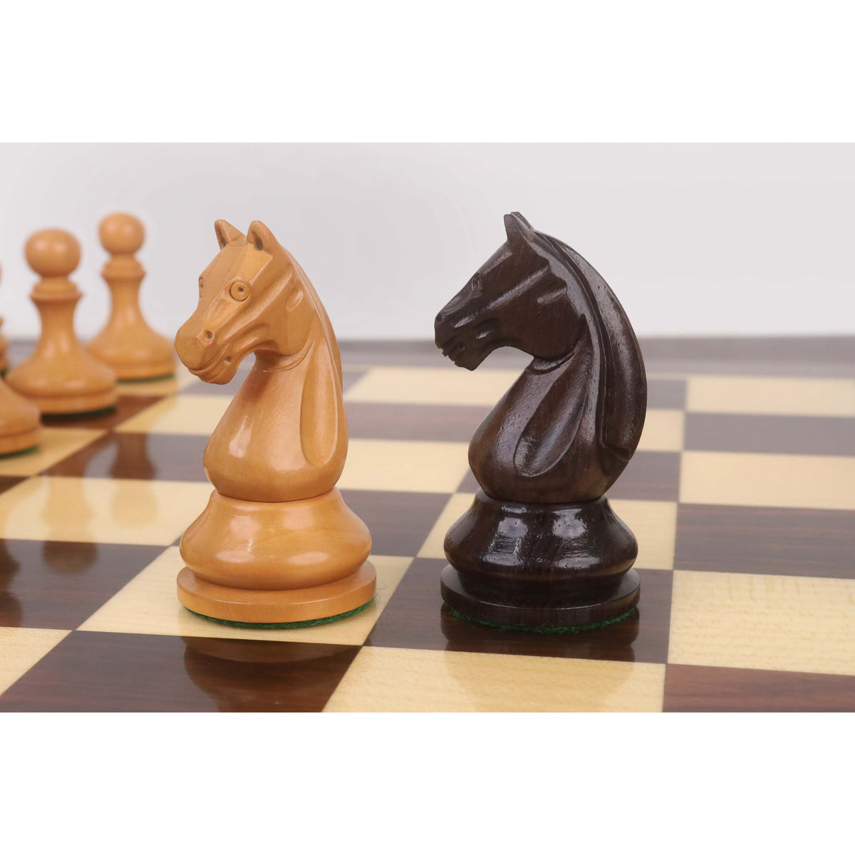 Profile close-up of rosewood and antiqued boxwood knights from the Candidates Series minimalist chess set facing each other.