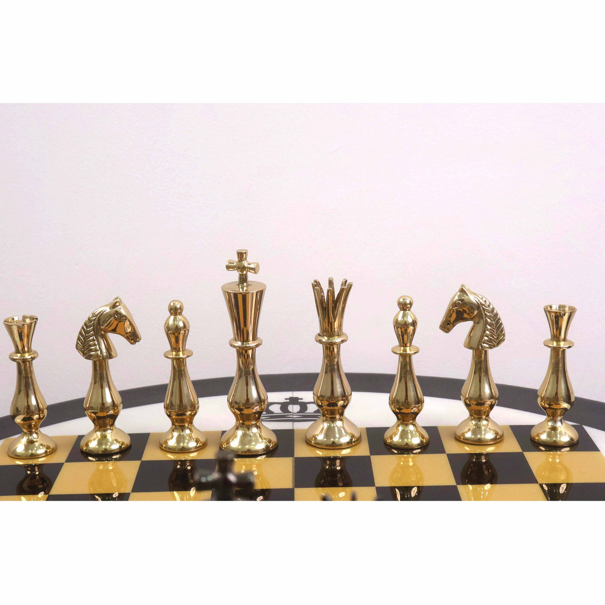 Gold brass chess pieces arranged on a luxury black and gold chess board.