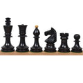 Elegant Romanian Hungarian chess pieces crafted from dark ebonised boxwood displayed on a wooden strip.
