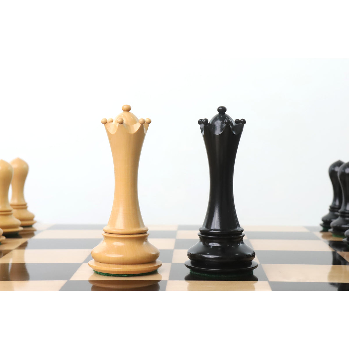 Elegant ivory and black Avant Garde chess Queens on a wooden board.