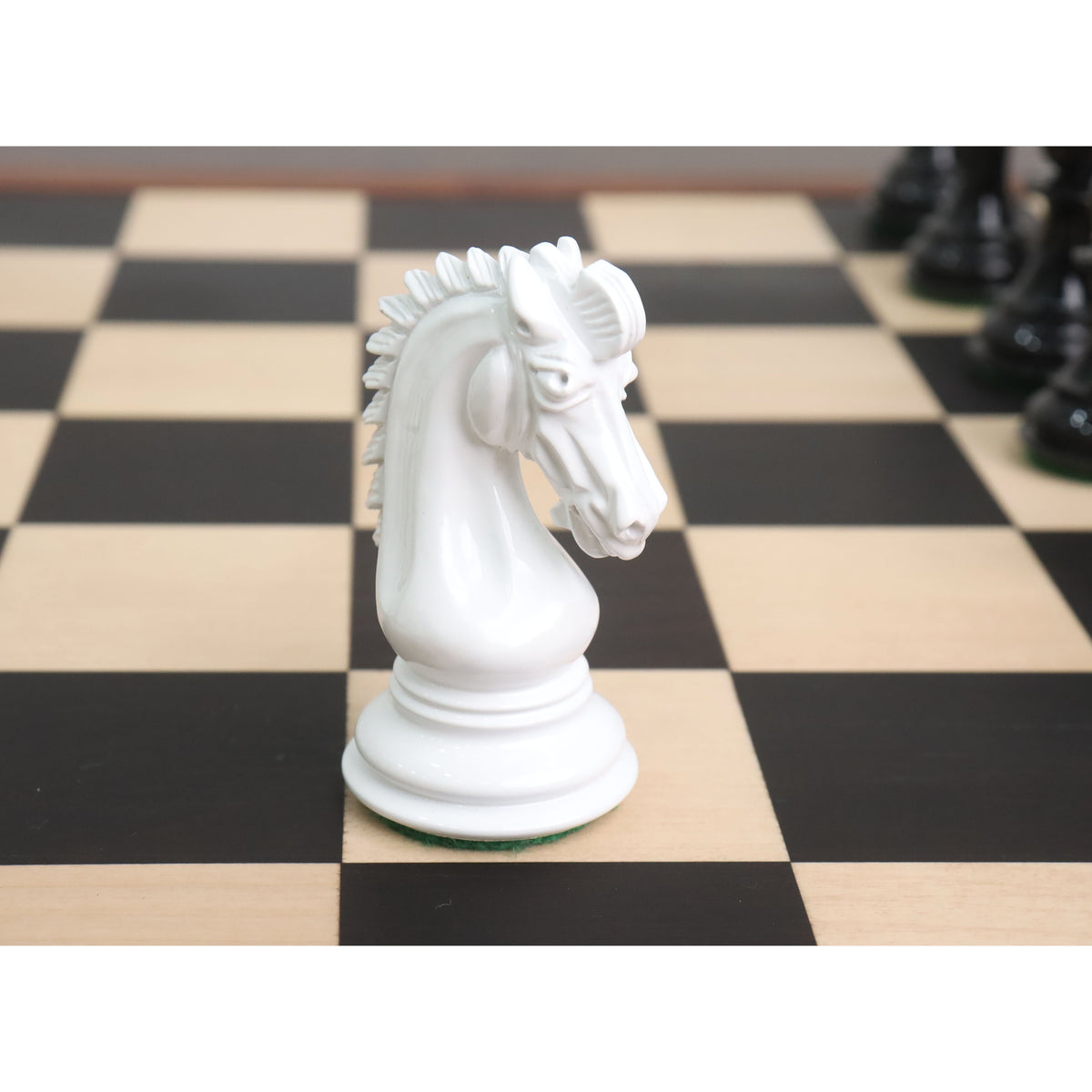 Close-up profile of a white texture painted Staunton Knight chess piece facing right on a wooden chessboard.