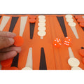 Close-up of a player holding an orange backgammon checker on the game board.