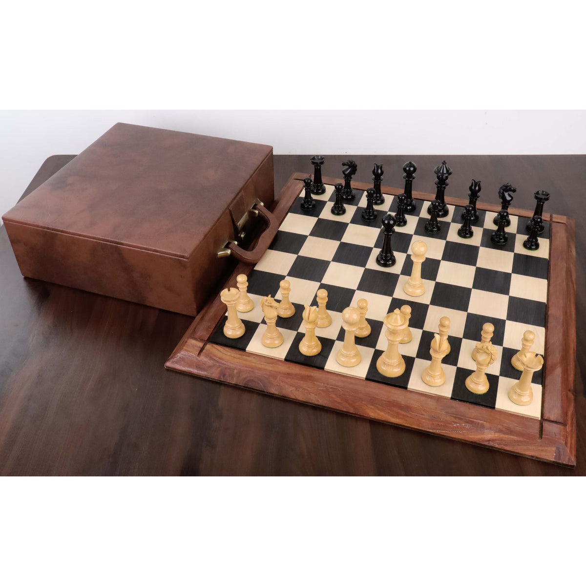 Edinburgh upright chess set arranged on a wooden board next to its luxury brown leather storage case.