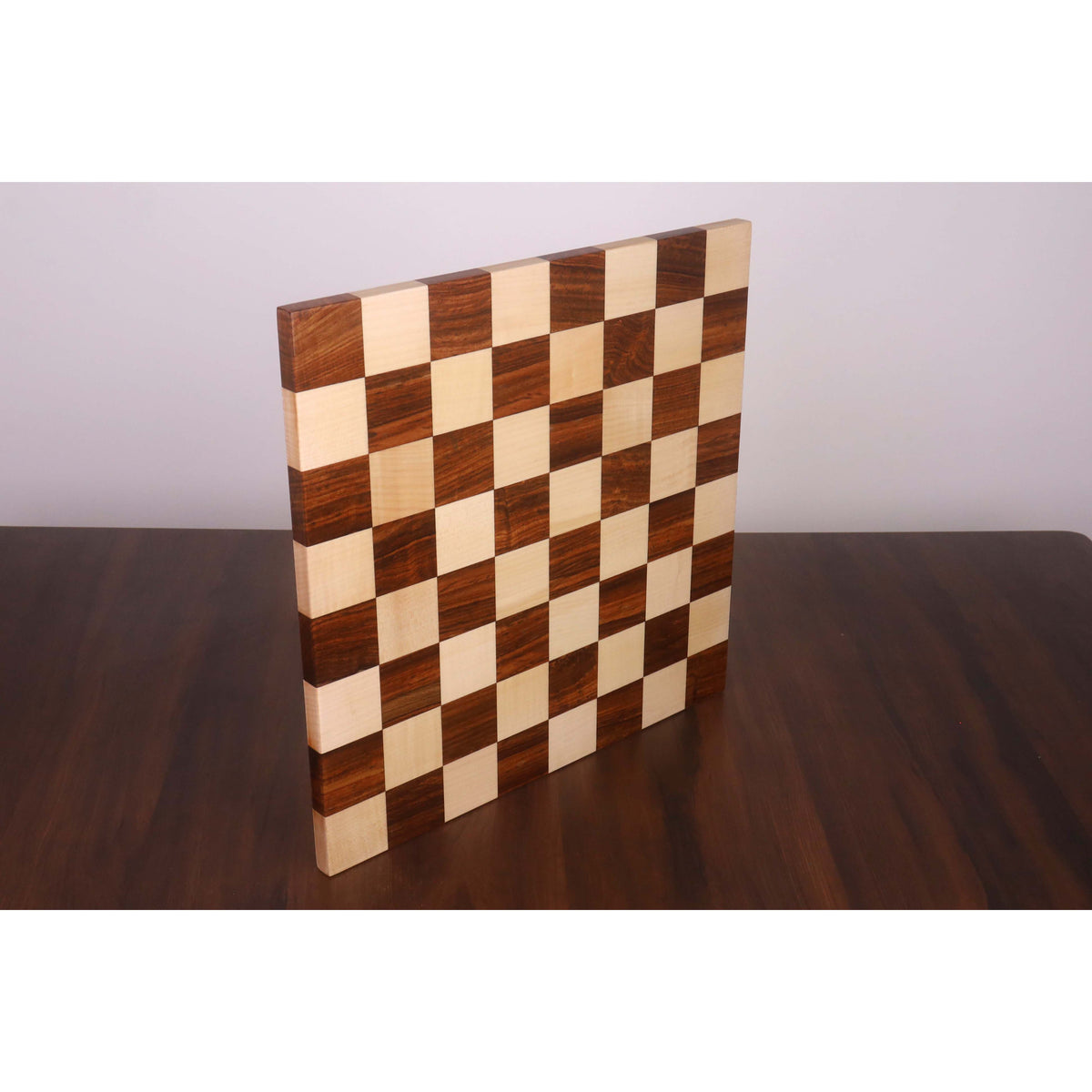 Borderless end grain chess board standing vertically to display its thick solid wood profile.