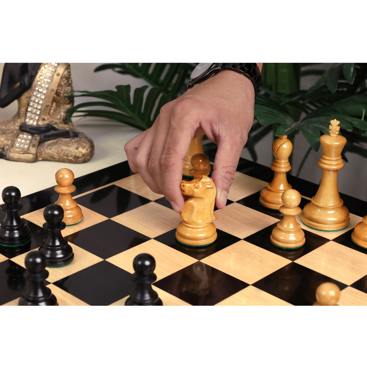 Hand moving a premium lacquered boxwood knight on a luxury chess board.