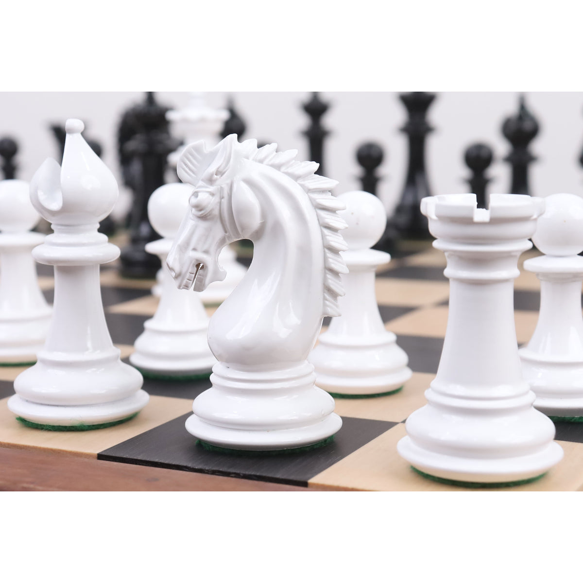 Close-up of a white texture painted Staunton Knight standing among other white chess pieces on a board.