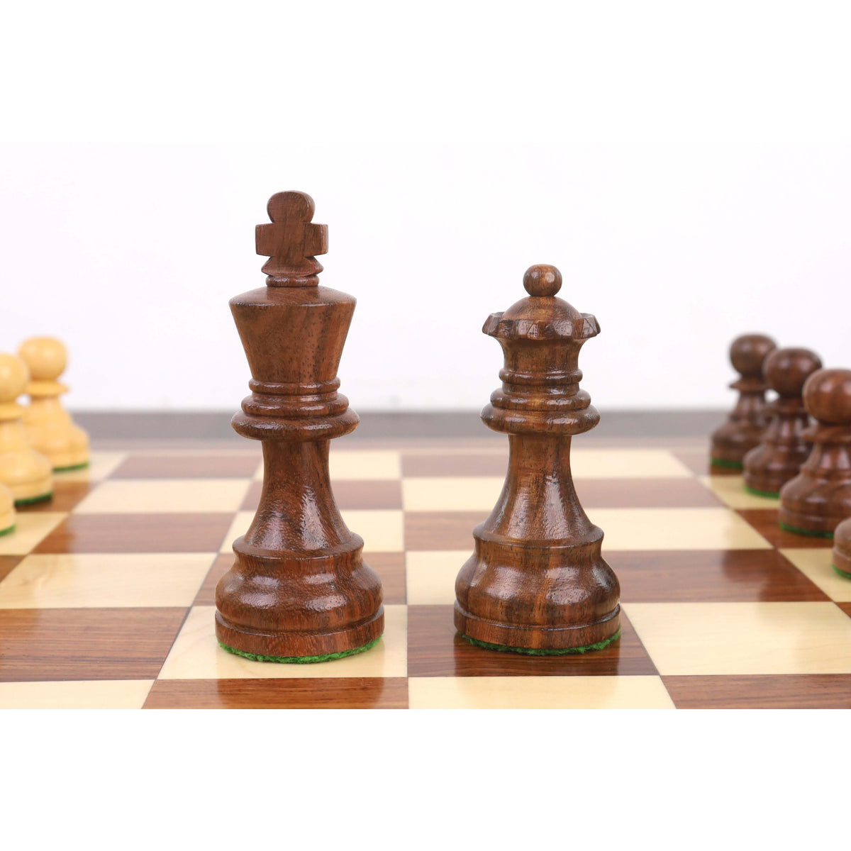A detailed close-up of the Golden Rosewood King and Queen Staunton chess pieces standing together on the chessboard.