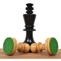 Ebonised boxwood King standing behind two overturned natural boxwood chess pieces revealing green felt pads.