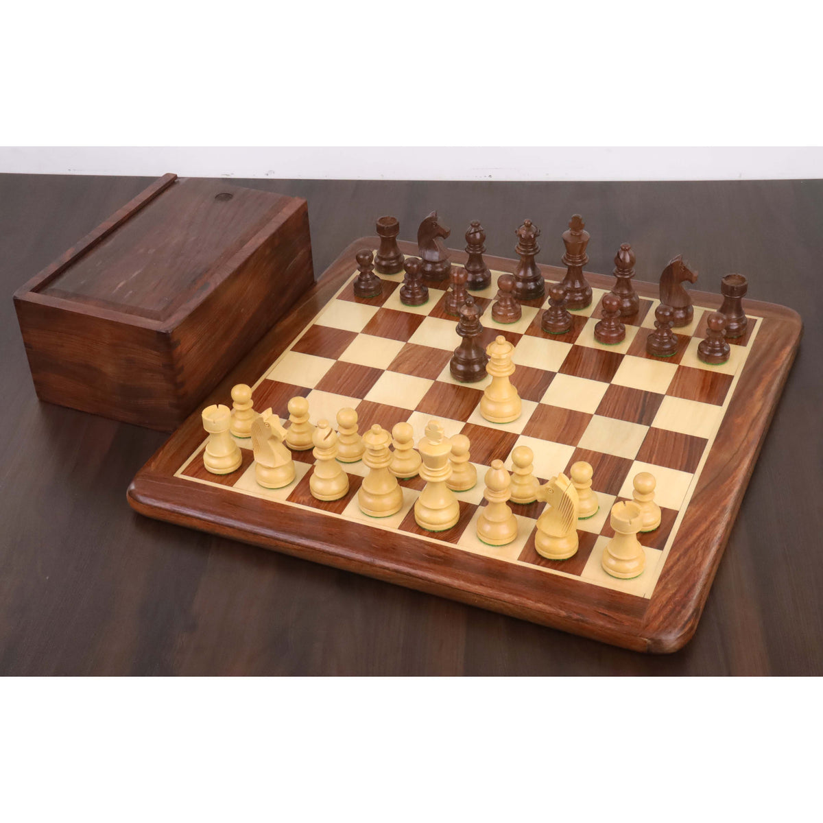 A complete 3.3" Golden Rosewood Staunton chess set setup on its wooden board with the storage box, against a dark background.