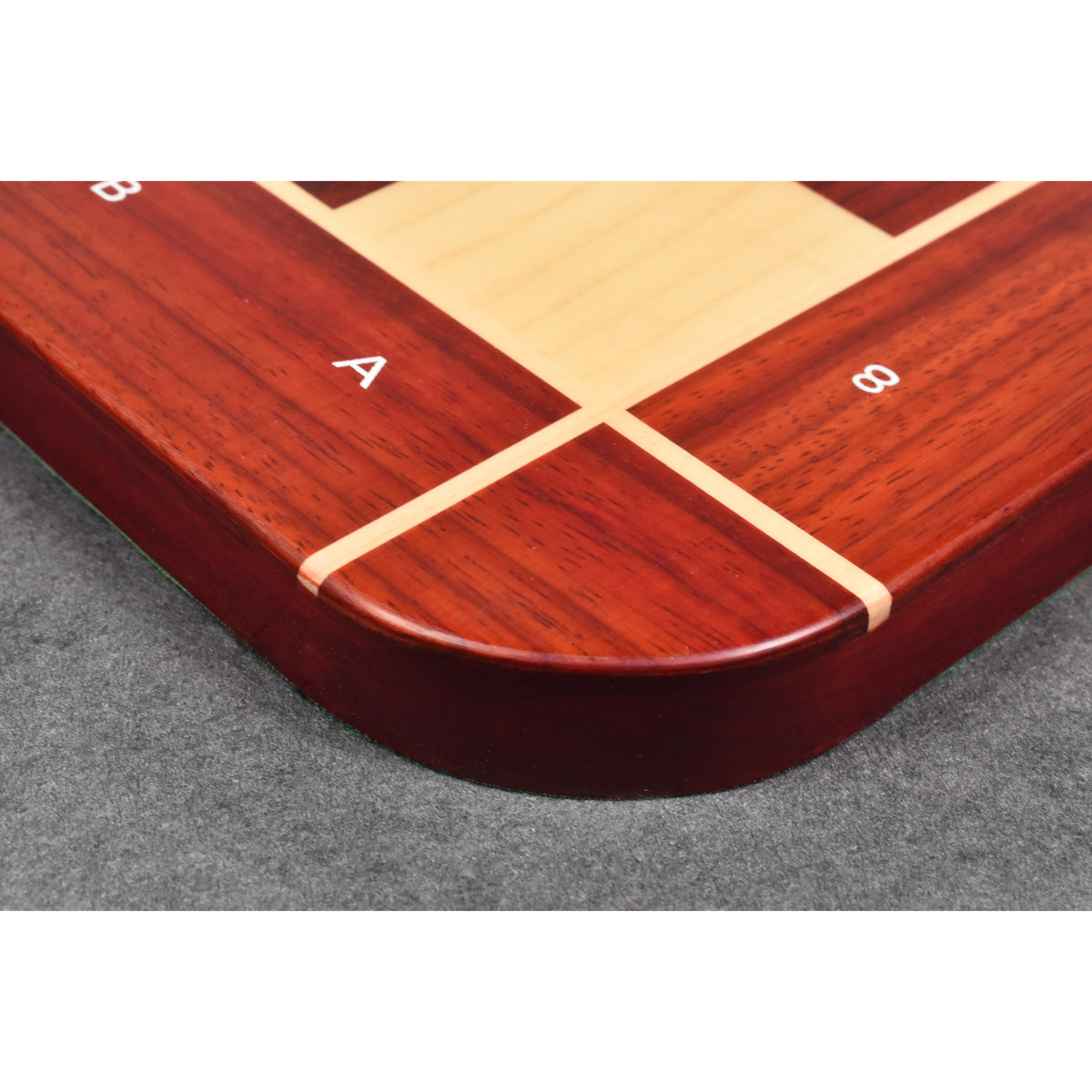 Macro detail of the rounded corner and smooth finish of a Bud Rosewood chess board with inlaid Maple border.