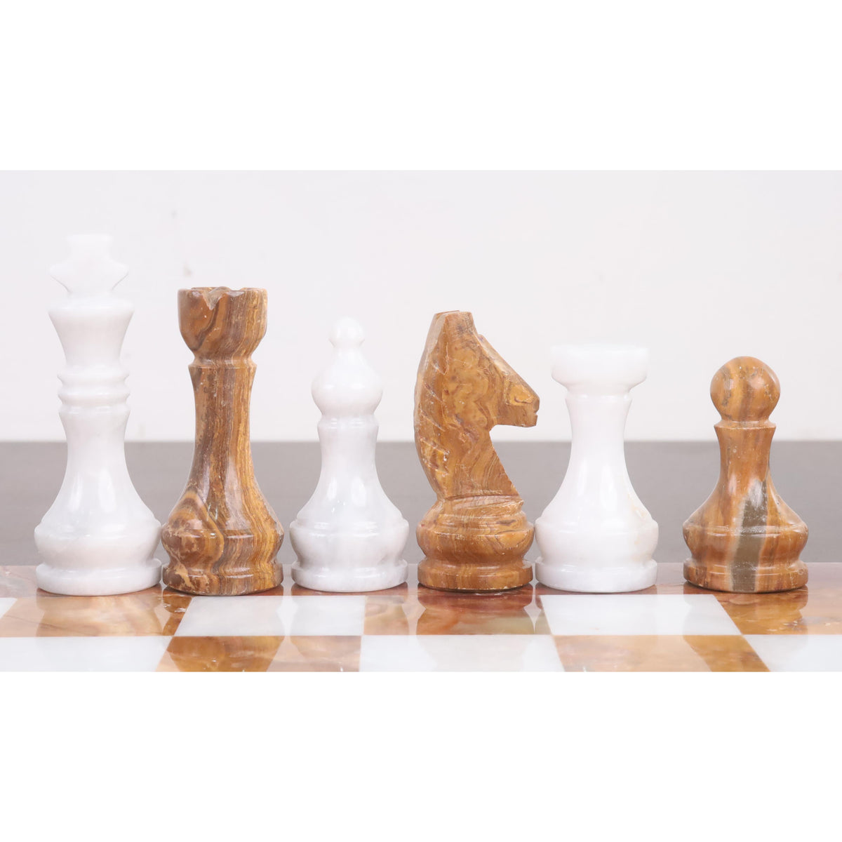 Lineup of white marble and brown onyx stone chess pieces showcasing distinct shapes and polished finishes.