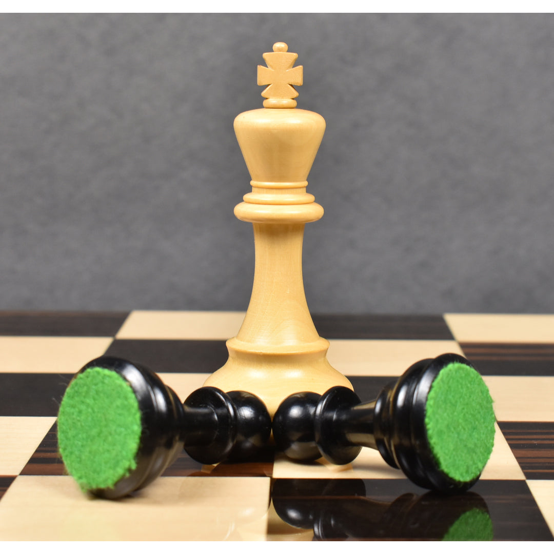 Standing light boxwood King behind two fallen ebonised pawns showing green felt bases from the Craftsman Staunton set.