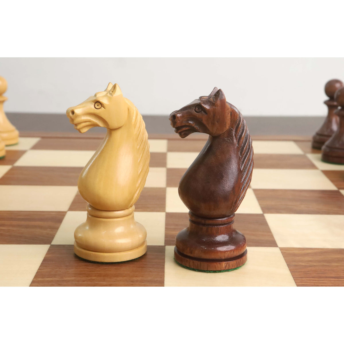Hand-carved wooden chess knights facing each other on a luxury board