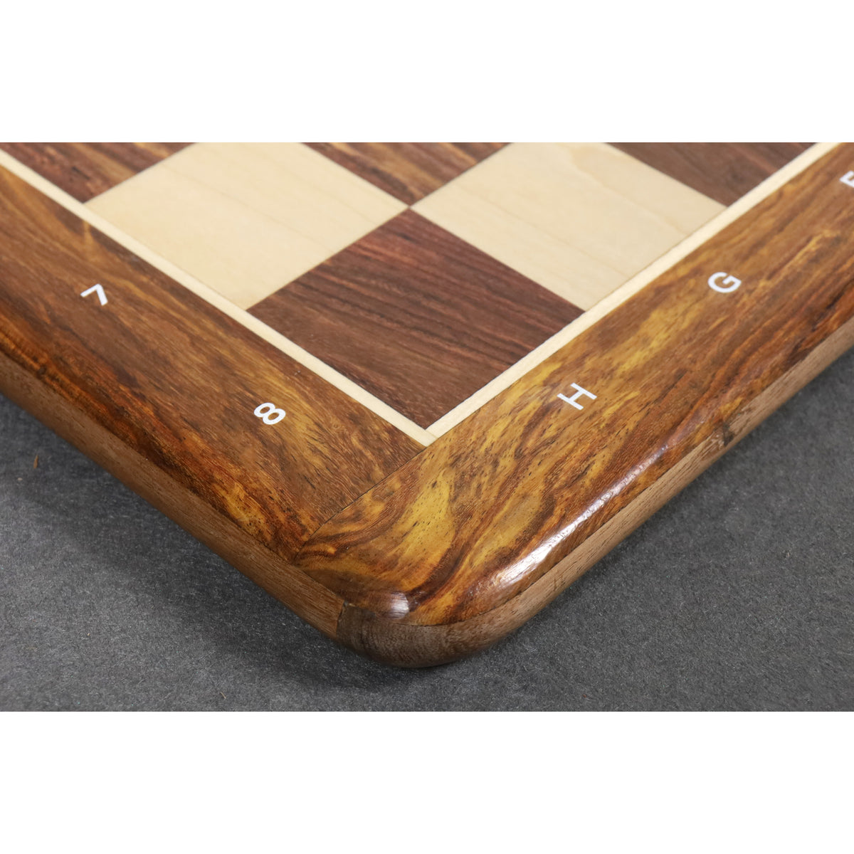Detailed macro shot of the rounded corner and natural wood grain of the Golden Rosewood chess board border.