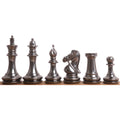 Lineup of grey luxury brass metal chess pieces showing sleek metallic contours from king to pawn on a white background.