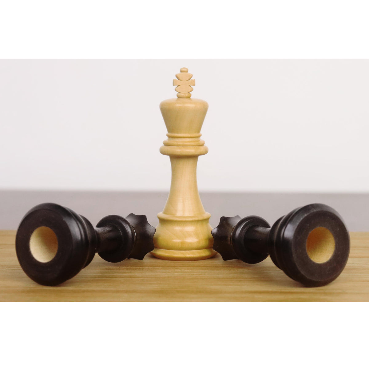 3 inch Craftsman Staunton King in boxwood standing over two fallen ebonised boxwood Queens.