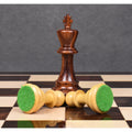 One dark king standing with two light pawns lying on their side on the chessboard.
