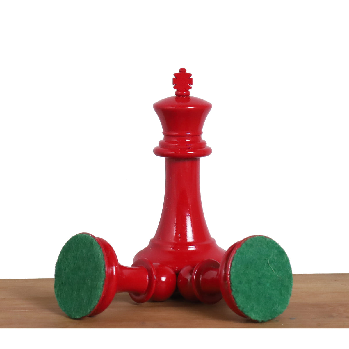 Underside of a red Staunton chess piece showing protective green felt padding.