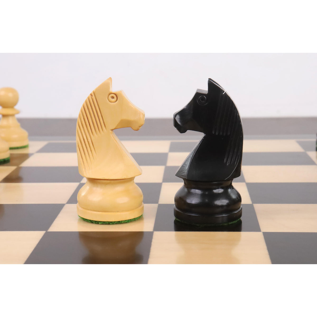 Close-up of opposing black and white knights from the Tournament Staunton chess pieces set facing each other.