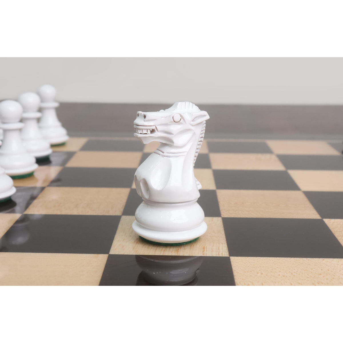 Close-up of a hand-carved white Pro Staunton knight chess piece on a polished ebony chess board.