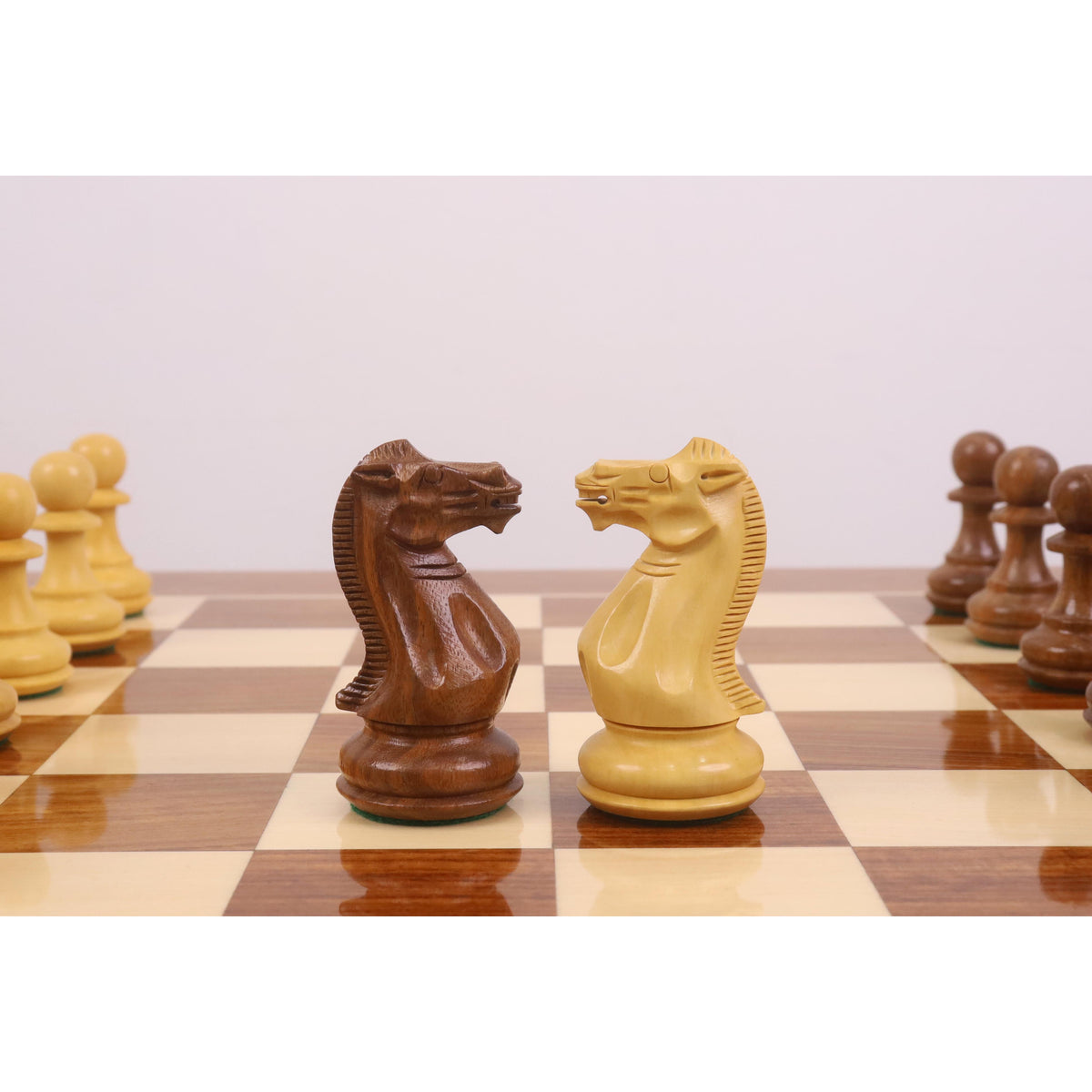 Detailed close-up of the hand-carved Pro Staunton Knights in Golden Rosewood and Boxwood on a glossy chess board.