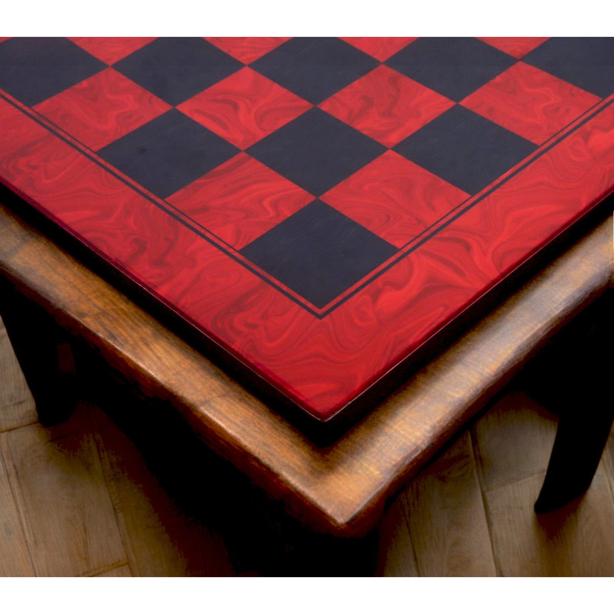Corner view of the red ash burl and ebony printed chess board placed on a dark wooden table.