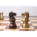 Copper and antique brass Pro Staunton metal chess knights facing each other on a wooden chessboard.