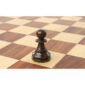 Close-up of a dark stained French Lardy pawn on a wooden board.