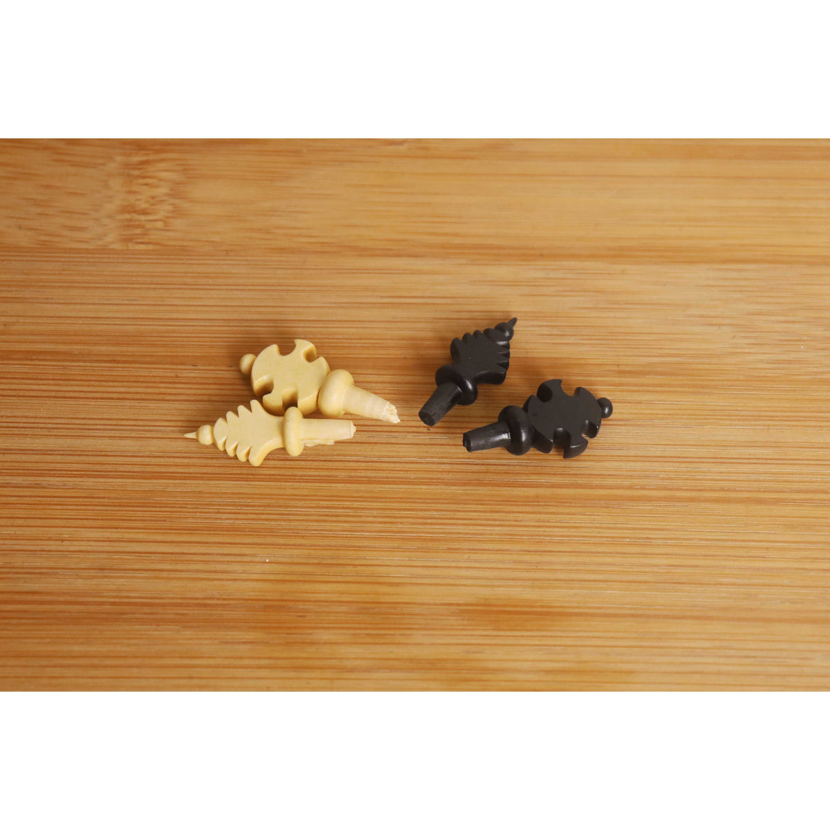 Threaded finial crown tops of boxwood and ebony chess Kings displayed on a textured wooden background.