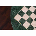 Detailed close-up of the hand-inlaid white semi-precious stone and green marble squares on a luxury round chess board.