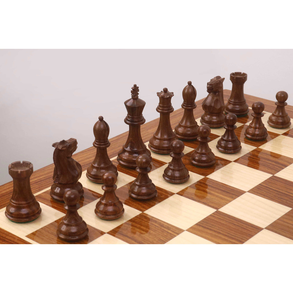 Dark golden rosewood Staunton pieces lined up on a Monarch series wooden chess table.