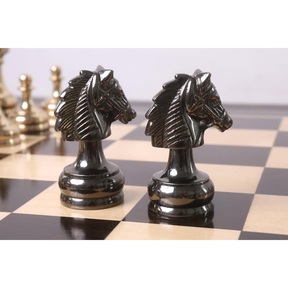 Two metallic grey knights from the Splendor Series brass luxury chess set positioned closely on a wooden chessboard.