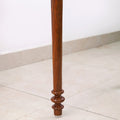 Macro view of the exquisite hand-turned leg detail of the Golden Rosewood chess table highlighting the natural wood grain.