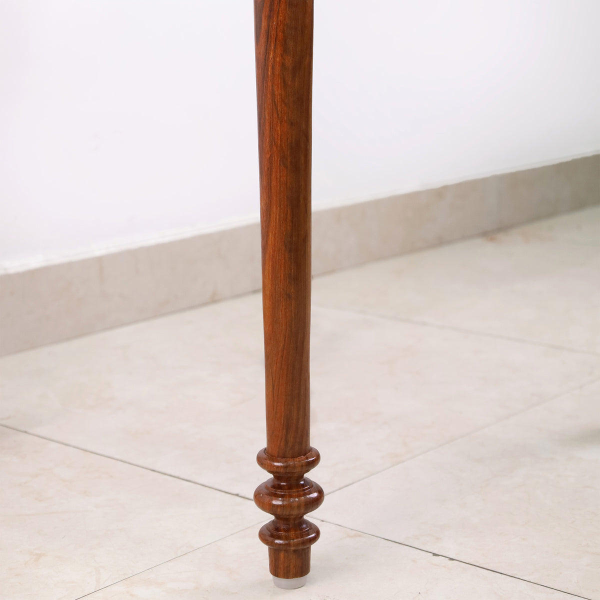 Macro view of the exquisite hand-turned leg detail of the Golden Rosewood chess table highlighting the natural wood grain.
