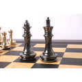 Polished grey metallic king and queen pieces from the Bridle series standing on a wooden chess board.