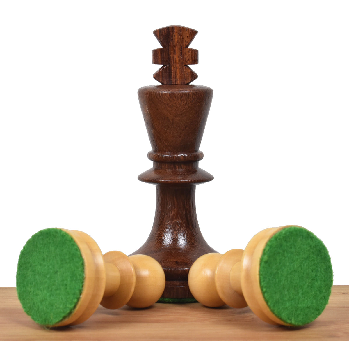 Two boxwood chess pieces overturned to show green felt bases next to a golden rosewood king.