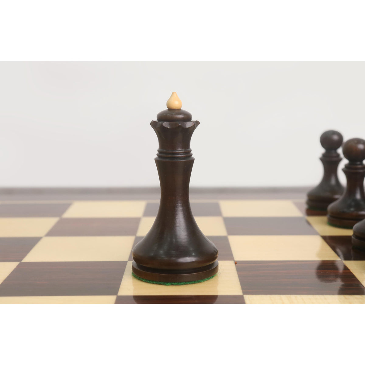 Close-up of the mahogany stained boxwood Queen from the 3.8" Candidates Series Minimalist chess set on a board.