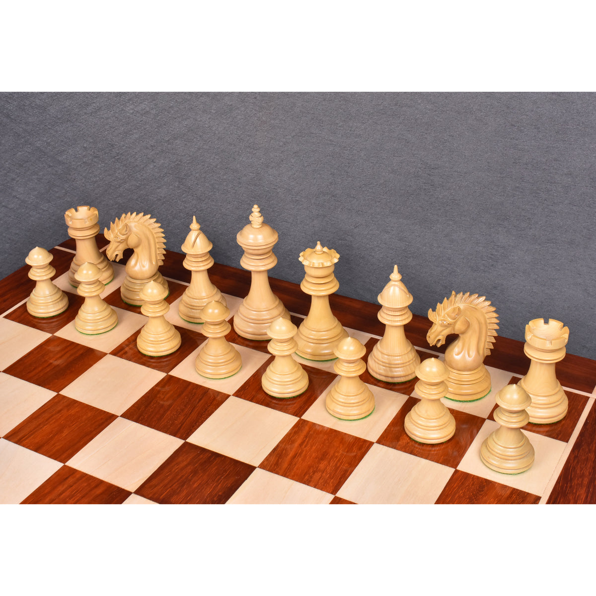 An elevated view of the Bud Rosewood Dragon chess pieces set up on a 23-inch wooden chessboard.