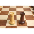 Golden rosewood and boxwood chess rooks standing on a wooden board