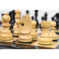 Detailed view of a natural boxwood knight piece on a glossy ebony and maple wooden chess board.