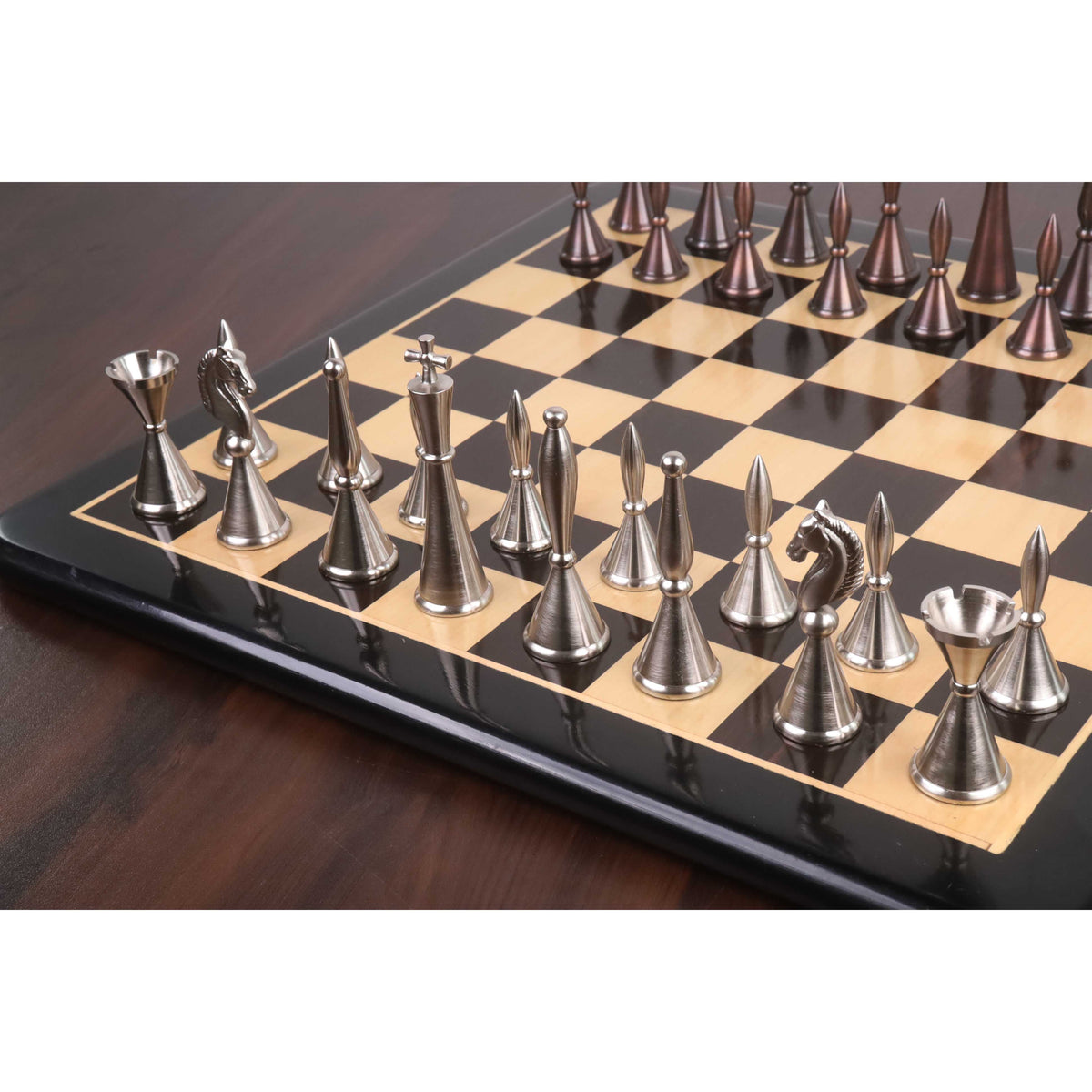 Luxury metal chess pieces arranged on a polished wooden chess board.