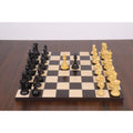 Sleek Staunton ebony and boxwood chess pieces set up in play on a wooden board.