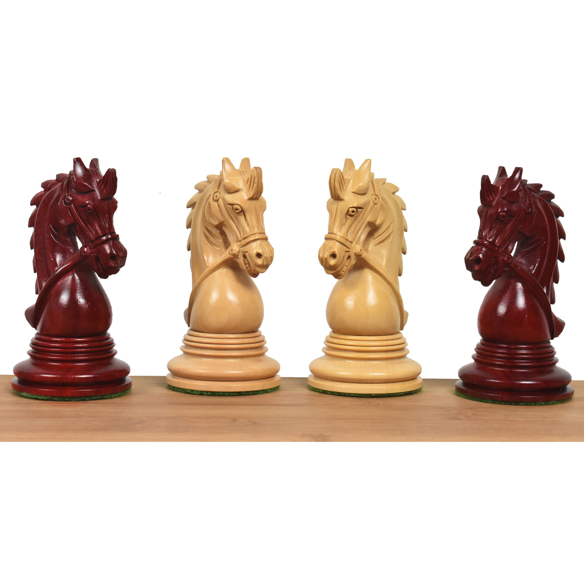 A profile lineup of four intricately carved Napoleon Luxury Staunton knights in Bud Rosewood and Boxwood on a wooden surface.