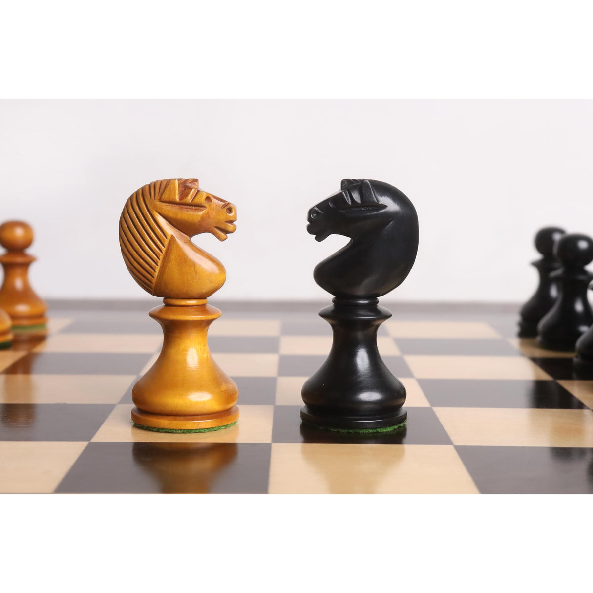 Antiqued and Ebonised English Dublin Knights facing each other on a wooden chessboard.
