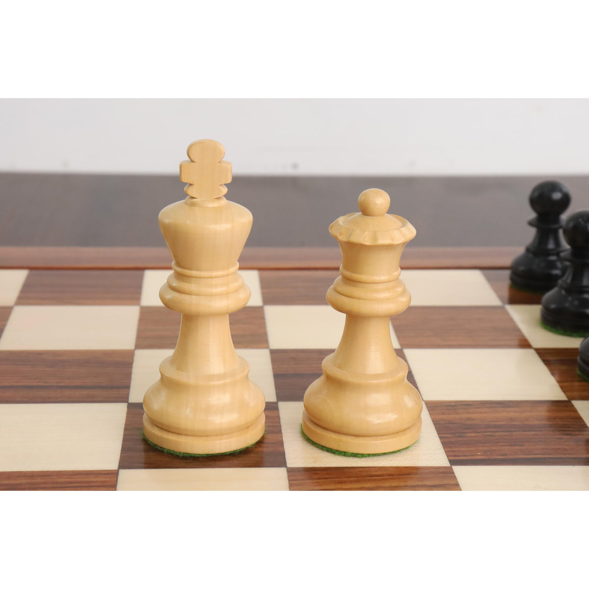 White Staunton king and queen chess pieces on a wooden board.