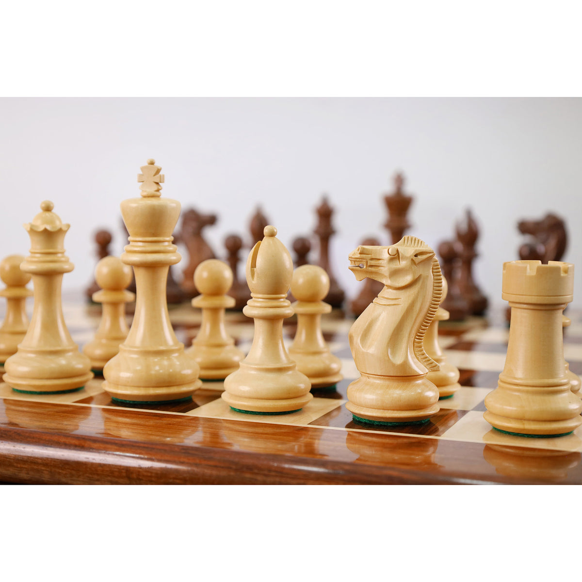 Detailed view of a light staunton chess knight and rook on a rosewood board.