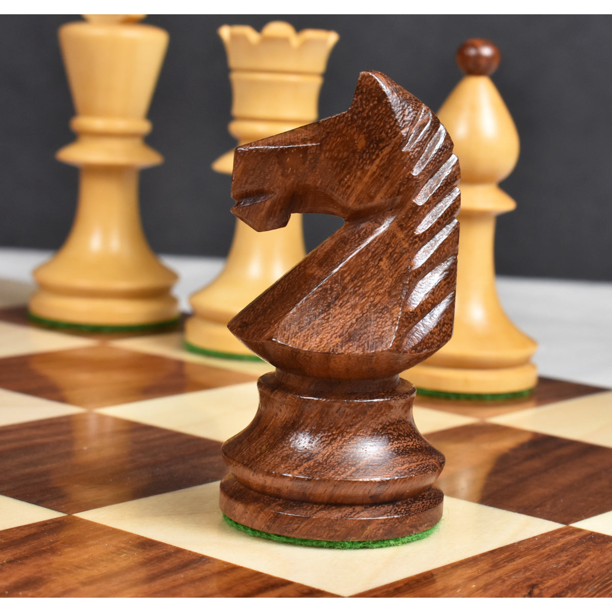Close-up of a hand-carved golden rosewood knight chess piece on a board with soft background bokeh.