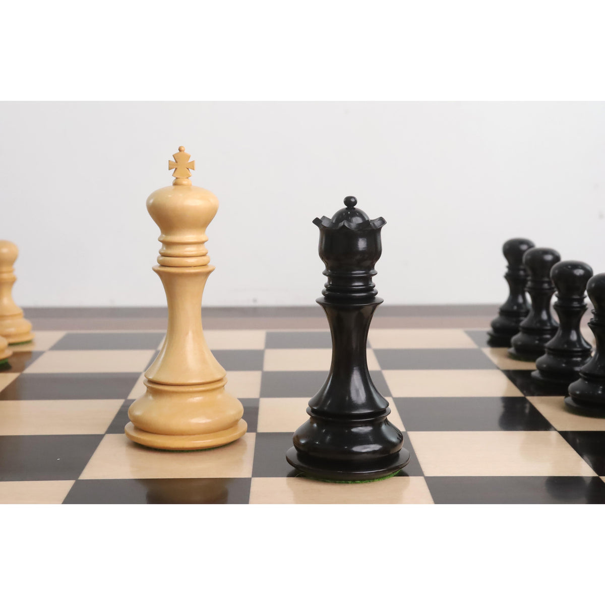 Goliath Series white King and black Queen Staunton chess pieces positioned on a wooden chessboard.